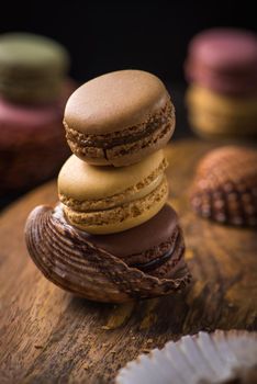 Column with cracked macaroons in sea shells on wooden background with soft focus.