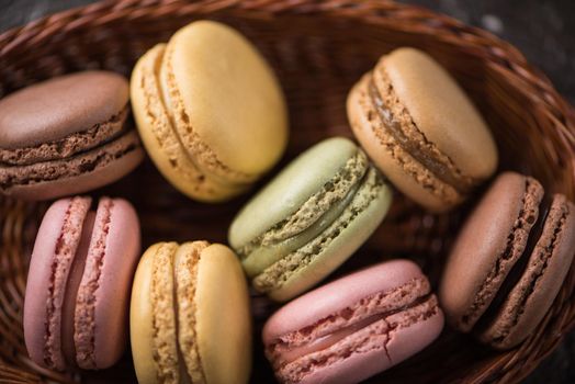 Top close view of macaroons on wicker basket background soft focus.