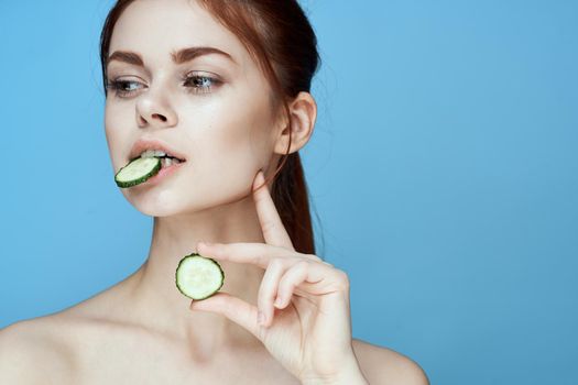 woman with bare shoulders cucumber vitamins health blue background. High quality photo