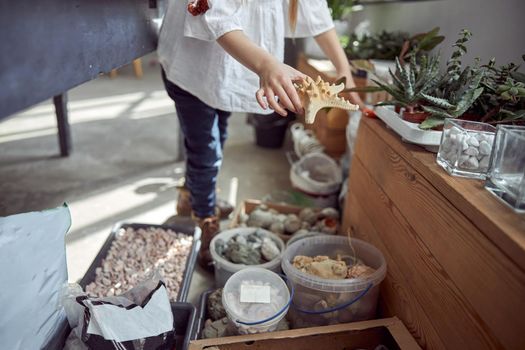 Hands of young caucasian girl who is working to do a composition.Flourist shop with different kinds of dryed flowers