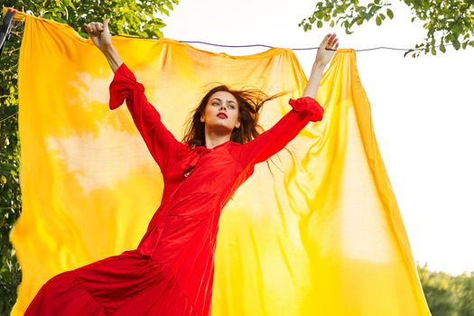 beautiful woman posing in red dress outdoors yellow cloth. High quality photo