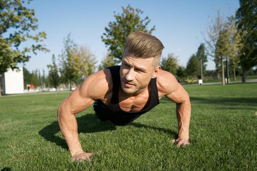 athletic man pumped up body in the park workout fitness fresh air. High quality photo