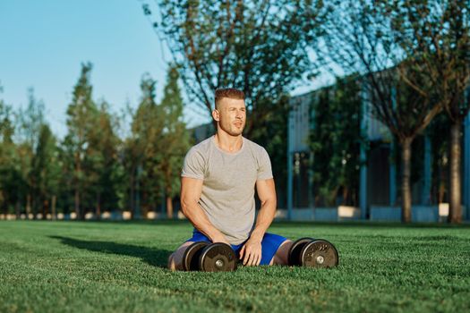 athletic man with dumbbells in the park exercise motivation. High quality photo