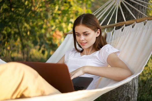 women outdoors lies in a hammock with a laptop freelance internet. High quality photo