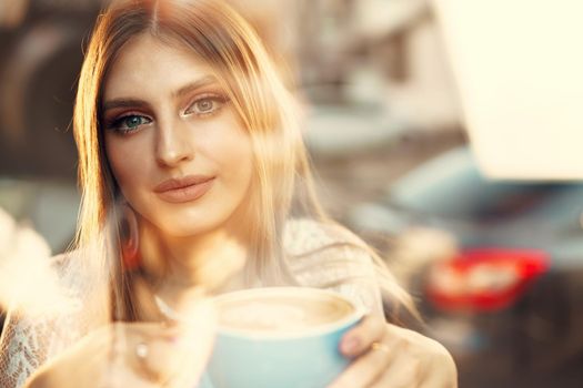 Portrait of a young woman having a cup of coffee and looking through the window. High quality photo