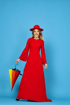 woman in red dress multicolored umbrella blue background. High quality photo