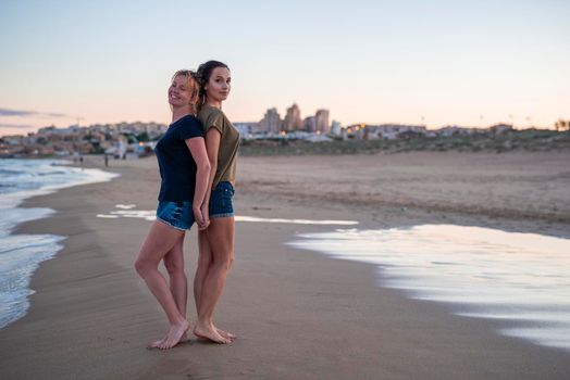 Two pretty young girls pretty best friend women having fun on their summer vacation on Mediterranean sea, mini denim shorts, amazing blonde and brunette hairs, traveling experience, happy emotions.