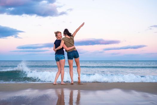 Two pretty young girls pretty best friend women having fun on their summer vacation on Mediterranean sea, mini denim shorts, amazing blonde and brunette hairs, traveling experience, happy emotions.