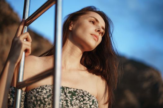 Young pretty woman in floral dress posing on yacht in the sea