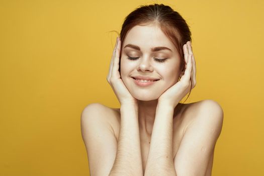 woman with bare shoulders clean skin hairstyle posing yellow background. High quality photo