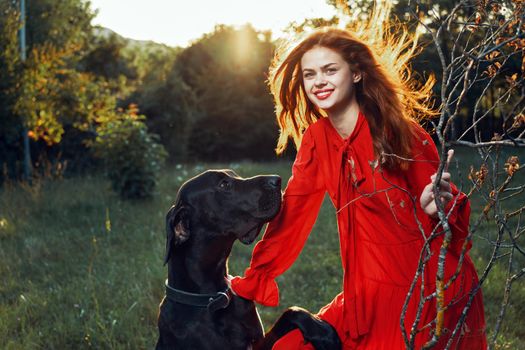 pretty woman in red dress with dog outdoors posing glamor. High quality photo