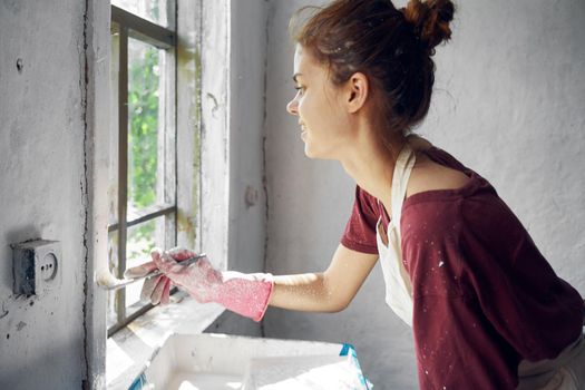 woman painter makes home repairs near window interior. High quality photo