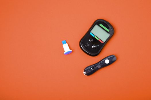 blood glucose meter and spare lancet needles on a red background copy space top view