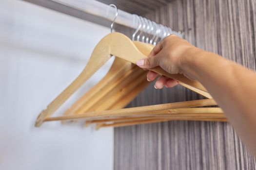 Wooden hangers in an empty open cabinet, hand taking a hanger. Clothing, fashion, shopping, new home, wardrobe organization concept