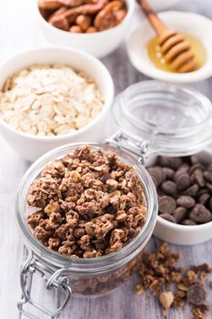 Homemade chocolate granola ingredients, nuts, oats, honey on white wooden background. Healthy breakfast concept.