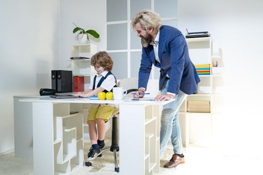 Group of four business colleagues in suits working on project. Cute boy kid sitting in office chair self confident like big boss, funny businessman bossy child, director and leader humorous concept