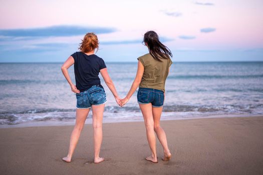 Two pretty young girls pretty best friend women having fun on their summer vacation on Mediterranean sea, mini denim shorts, amazing blonde and brunette hairs, traveling experience, happy emotions.