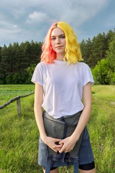 Portrait of a teenage girl hipster 15, 16 years old with dyed hair, dramatic sky nature background