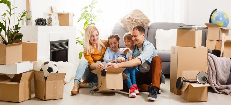 Happy family with cardboard boxes in new house at moving day.