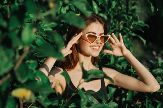 smiling woman wearing sunglasses green leaves nature fashion. High quality photo