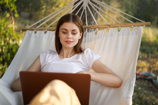 woman working in front of laptop in a hammock in nature. High quality photo