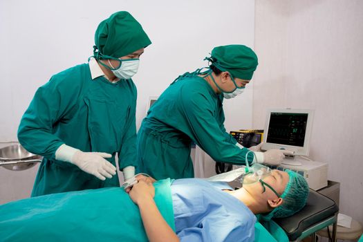 Team doctor and assistant preparation surgery and oxygen mask with patient emergency in the operation room at hospital, surgeon healing and surgery with looking monitor, problem of breathing.