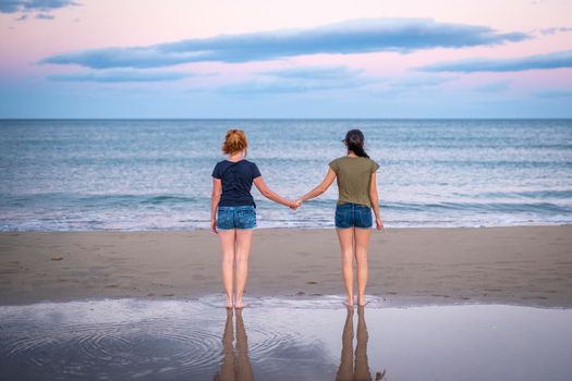 Two pretty young girls pretty best friend women having fun on their summer vacation on Mediterranean sea, mini denim shorts, amazing blonde and brunette hairs, traveling experience, happy emotions.