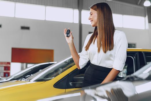 Young attractive woman buying a new car in car salon close up