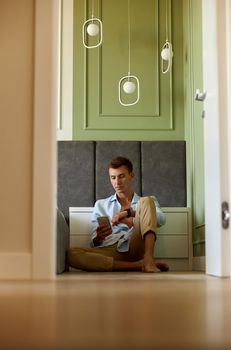 Young adult happy man in near olive wall is having time and smiling