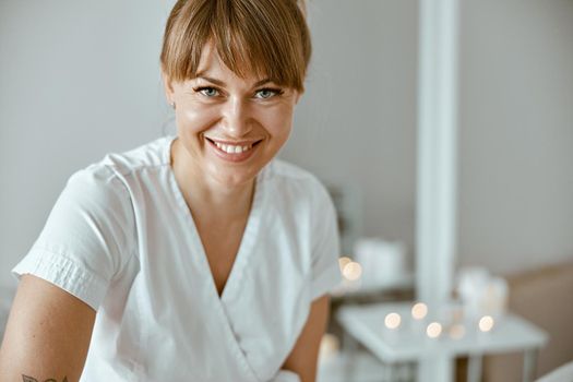 confident female specialist is doing relaxing body massage for beautyful slim caucasian lady at minimalistic spa salon