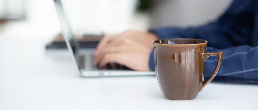 Hand of business man working from home using laptop computer to internet online on desk, lifestyle of new normal, social distancing, freelance work in stay home, employee using notebook indoor.