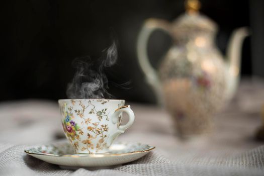 Porcelain tea pot and cup of hot tea on the table, antique traditional crockery set, high tea English afternoon tea cozy stylish interior