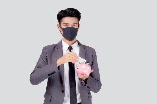 Young asian businessman in face mask holding money dollar and piggy bank isolated on white background, crisis of economic, business man in mask investment finance and saving during disease covid-19.