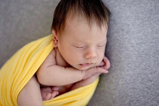 Lovely newborn sleeping wrapped up in yellow blanket