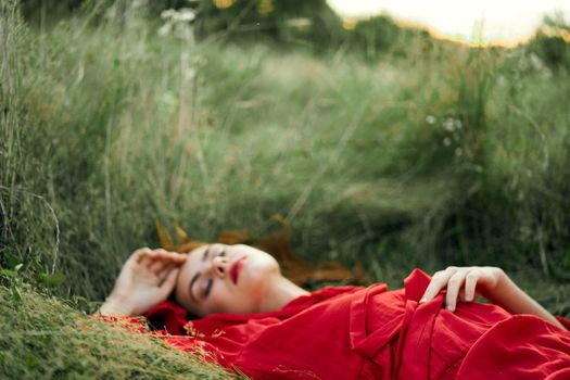 woman in red dress lying on the grass fresh air nature romance. High quality photo