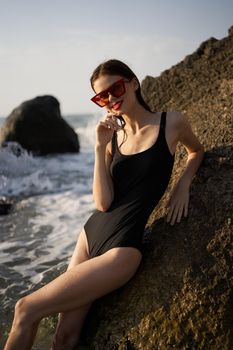 woman in swimsuit sunglasses ocean rocks posing. High quality photo
