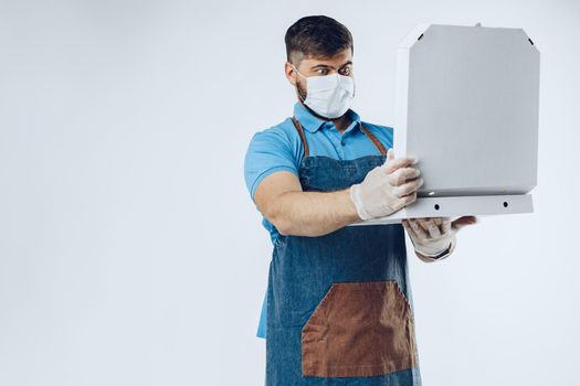 Pizza delivery man in medical gloves and mask against grey background. Safe service while coronavirus covid-19 outbreak