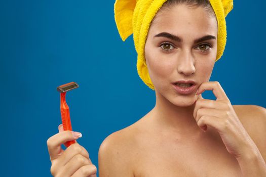 pretty woman with a yellow towel on his head shaving blue background. High quality photo