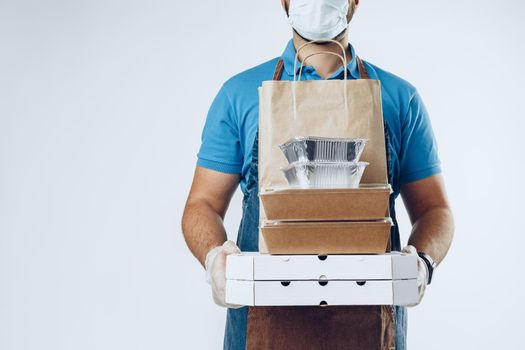 Unrecognizable man in blue polo shirt with food delivery orders against light grey background