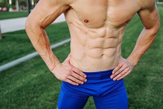 sporty man with pumped up abs in the park while workout exercise lifestyle. High quality photo