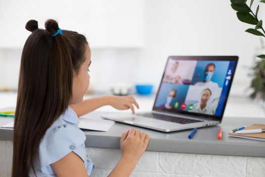 Pretty stylish schoolgirl studying homework math during her online lesson at home, social distance during quarantine, self-isolation, online education concept, home schooler