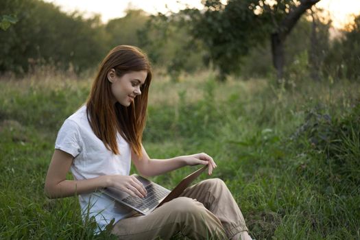 women outdoors in field with laptop leisure technology freedom. High quality photo