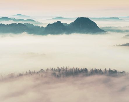 Landscape misty panorama. Fantastic dreamy sunrise on rocky mountains with view into misty valley below 