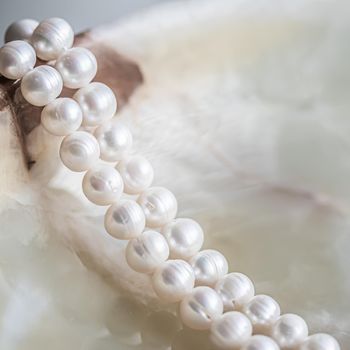 Nature white string of pearls on marble background in soft focus, with highlights