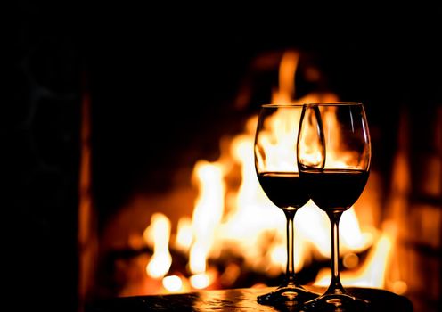Two glasses of red wine on the background of fireplace lights. Christmas holiday concept