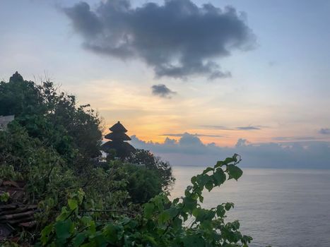 A scenic Uluwatu cliff with pavilion and blue sea in Bali - stock photo