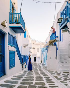 Mykonos Greece, Young man and woman in dress at the Streets of old town Mikonos during a vacation in Greece, Little Venice Mykonos Greece. couple mid age vacation Greece