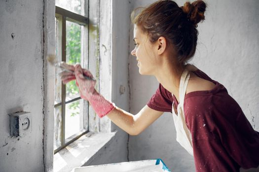 woman painter makes home repairs near window interior. High quality photo