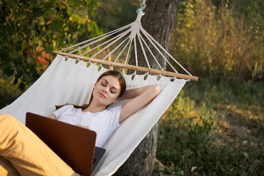 woman working on laptop in nature hammock freelance. High quality photo