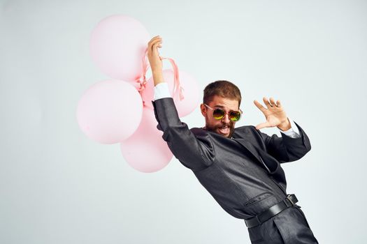 a man in a suit and sunglasses pink balloons manager holiday. High quality photo